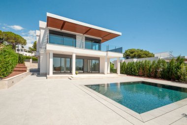 Geniş yüzme havuzlu lüks bir villanın modern cephesi. Lüks Modellik.