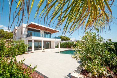 Geniş yüzme havuzlu lüks bir villanın modern cephesi. Lüks Modellik.