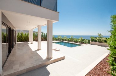 Geniş yüzme havuzlu lüks bir villanın modern cephesi. Lüks Modellik.