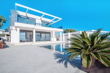 Geniş yüzme havuzlu lüks bir villanın modern cephesi. Lüks Modellik.