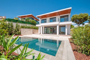 Geniş yüzme havuzlu lüks bir villanın modern cephesi. Lüks Modellik.