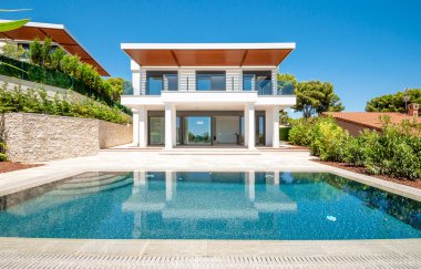 Geniş yüzme havuzlu lüks bir villanın modern cephesi. Lüks Modellik.