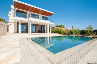 Geniş yüzme havuzlu lüks bir villanın modern cephesi. Lüks Modellik.
