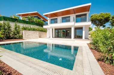 Geniş yüzme havuzlu lüks bir villanın modern cephesi. Lüks Modellik.