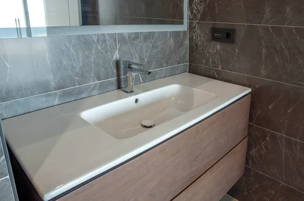 Modern white washbasin with mixer tap in bathroom.