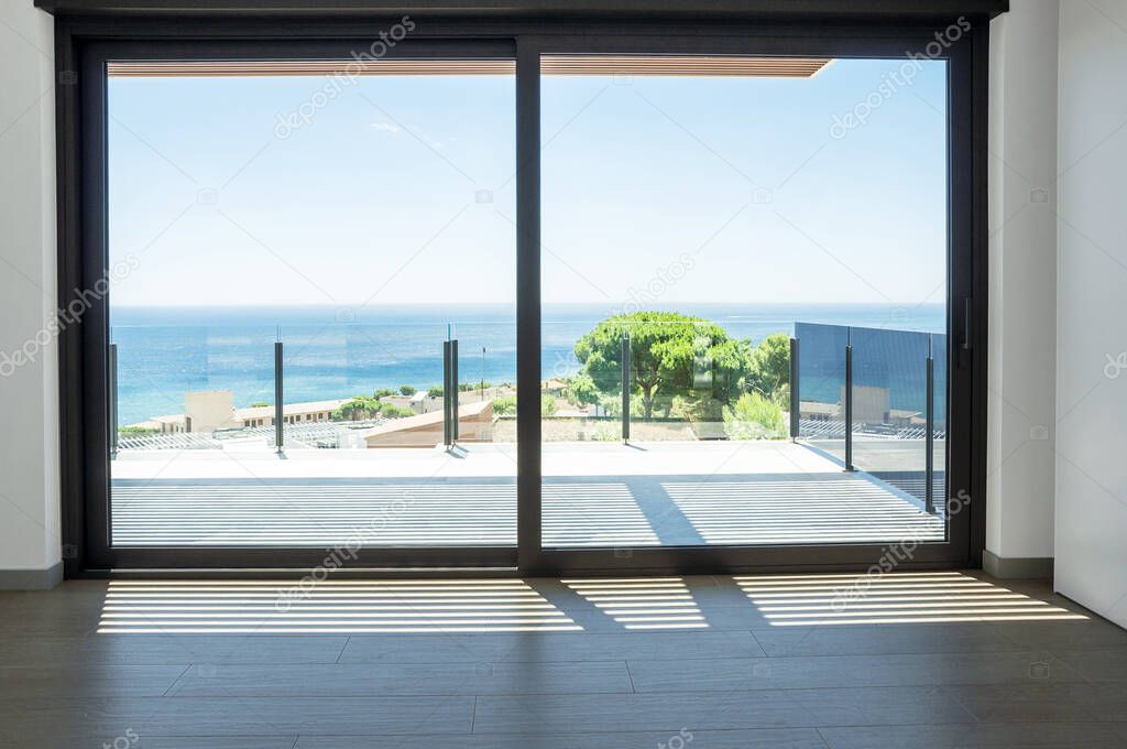 Empty room with large panoramic windows overlooking the sea. Room after major renovation. 