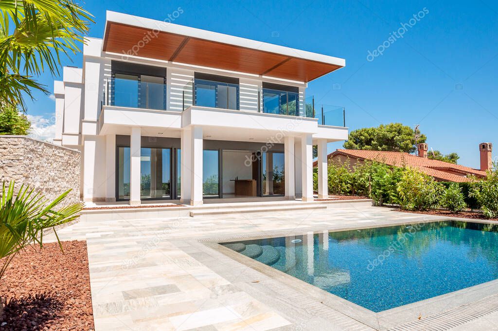 The modern facade of a luxury villa with a large swimming pool. Luxury MODERN property.