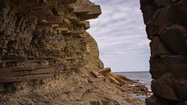 Kamera se pohybuje od skalnatého pobřeží s přílivovými jezírky k moři. S pláštěm v pozadí — Stock video