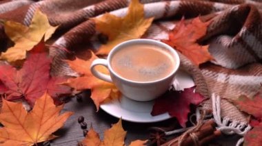 Sonbahar, sonbahar yaprakları, bir fincan sıcak kahve ve ahşap masa arkasında sıcak ekose. Mevsimlik, sabah kahvesi, pazar dinlendirici ve hayat konsepti. Çemberdeki kamera hareketi