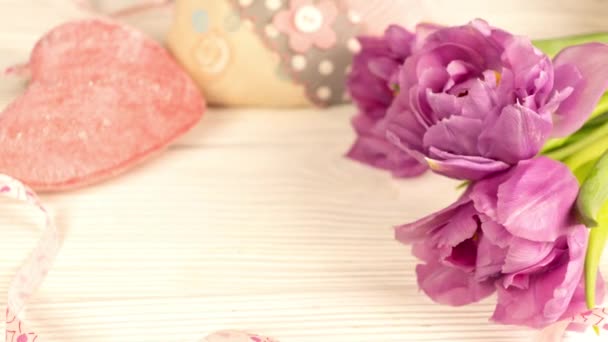 Top vista florescendo tulipas flores buquê e coração em uma mesa de madeira branca. Conceito de relacionamento amoroso. Dia de São Valentim. Tiros em 4K — Vídeo de Stock