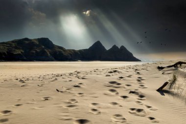Gower Yarımadası, Güney Galler, U 'daki Three Cliffs Körfezi' nde dramatik gökyüzü ve ayak izleri.