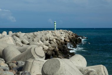 Funchal, Madeira, Portekiz 'deki yeşil ve beyaz deniz feneri ve beton deniz savunması.