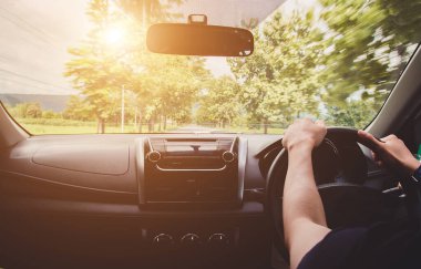 Otobanda dikiz aynasından araba süren bir adam yaz yolu boyunca manzaralı bir yerde araba sürüyor. Yaz gezisi.