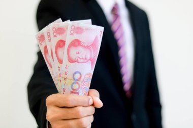 Elinde para, Yuan, yatırım, başarı ve karlı iş kavramları olan bir iş adamı..