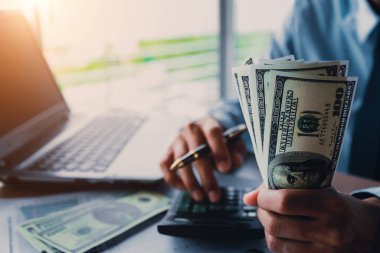 Elinde para, Amerikan doları, yatırımı, başarısı ve karlı iş kavramları olan bir iş adamı.