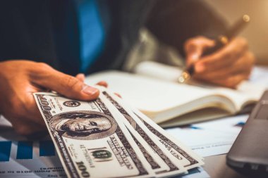 Elinde para, Amerikan doları, yatırımı, başarısı ve karlı iş kavramları olan bir iş adamı.