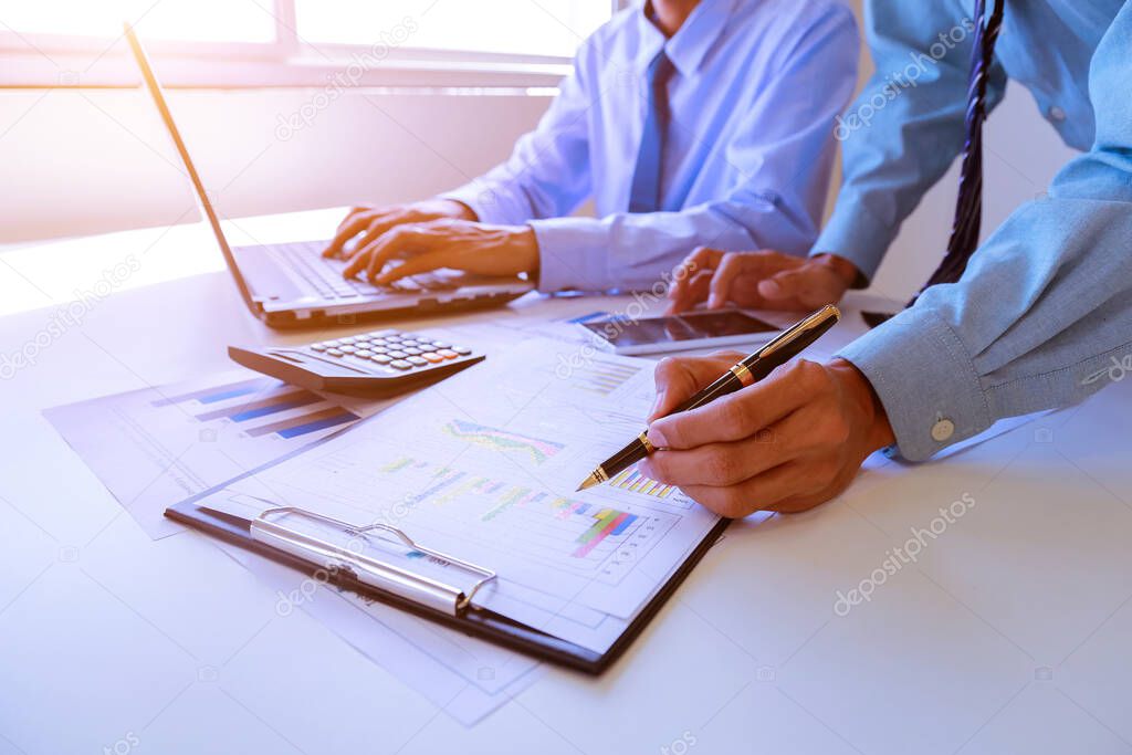 Two business man people working analyzing and calculate summary of cost from document chart and graph with calculator at office, Accounting and finance in the office.