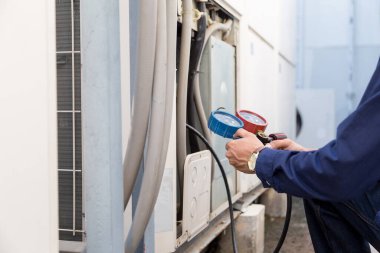 Teknisyen klimayı kontrol ediyor, klimaları doldurmak için ekipmanları ölçüyor..