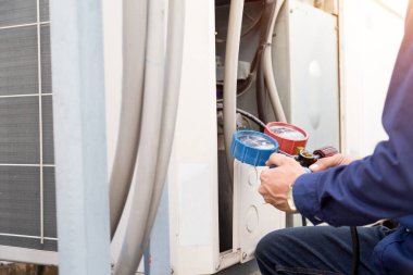 Teknisyen klimayı kontrol ediyor, klimaları doldurmak için ekipmanları ölçüyor..
