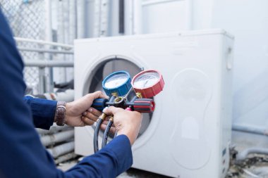 Teknisyen klimayı kontrol ediyor, klimaları doldurmak için ekipmanları ölçüyor..