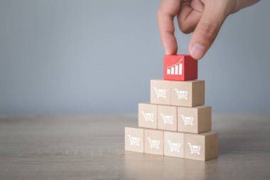 Hand arranging wood block stacking with icon Graph and shopping cart symbol upward direction,