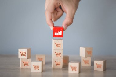Hand arranging wood block stacking with icon Graph and shopping cart symbol upward direction,