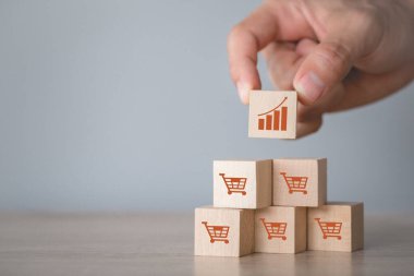 Hand arranging wood block stacking with icon Graph and shopping cart symbol upward direction,