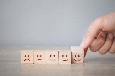 Customer pressing smiley face emoticon on wood cube, Service rating, satisfaction concept.