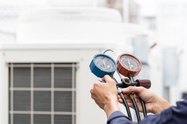 Teknisyen klimayı kontrol ediyor, klimaları doldurmak için ekipmanları ölçüyor..