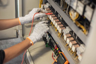 Elektrik mühendisi elektrik sistemi kontrol dolabındaki elektrik akımını ve elektrik hattını test etmek için çoklu metre kullanıyor..