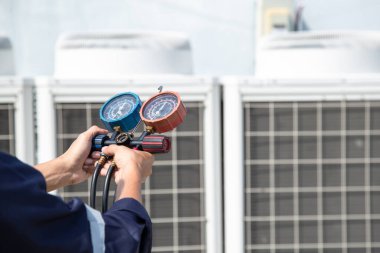 Teknisyen klimayı kontrol ediyor, klimaları, servis ve bakım klimalarını doldurmak için ölçüm aletleri kullanıyor. .