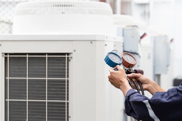 Teknisyen klimayı kontrol ediyor, klimaları doldurmak için ekipmanları ölçüyor..