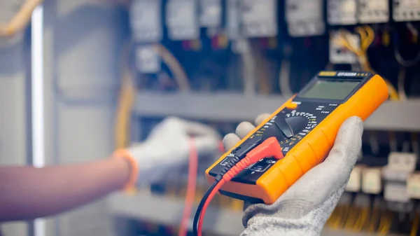 Elektrik mühendisi elektrik sistemi kontrol dolabındaki elektrik akımını ve elektrik hattını test etmek için çoklu metre kullanıyor..