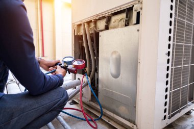 Teknisyen klimayı kontrol ediyor, klimaları doldurmak için ekipmanları ölçüyor..
