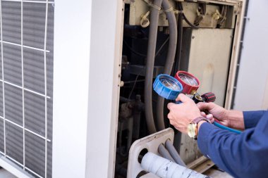 Teknisyen klimayı kontrol ediyor, klimaları doldurmak için ekipmanları ölçüyor..