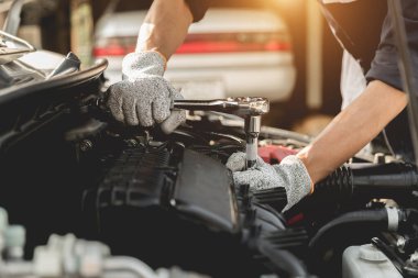 Otomobil tamircisi elleri ingiliz anahtarı, araba servisi ve bakımı ile bir araba motoru otomotiv atölyesini tamir ediyor..