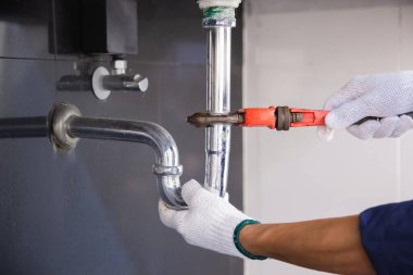 Tesisatçı ayarlanabilir anahtarla beyaz lavabo borusunu tamir ediyor..