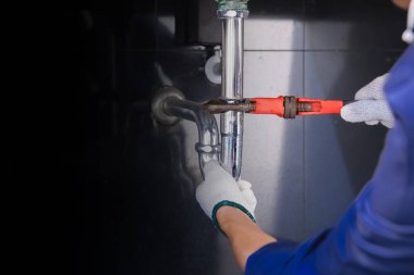 Tesisatçı ayarlanabilir anahtarla beyaz lavabo borusunu tamir ediyor..