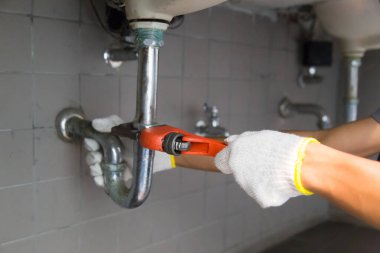 Tesisatçı ayarlanabilir anahtarla beyaz lavabo borusunu tamir ediyor..