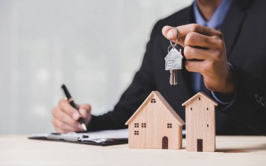 Buy or Rent 'le çalışan iş adamı, kopyalama alanı. Mülk yatırımı ve ev kredisi finansal konsepti El 'in ahşap eve para yığını koyması..