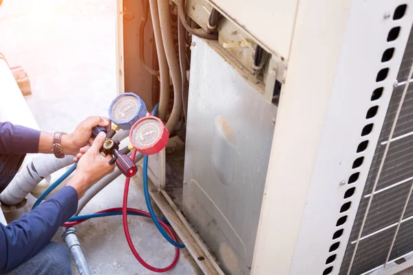 Teknisyen klimayı kontrol ediyor, klimaları doldurmak için ekipmanları ölçüyor..
