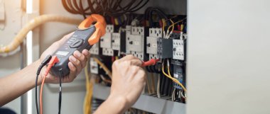 Elektrik mühendisi elektrik kabinesi kontrolündeki voltaj ve elektrik akımını ölçen bir testçi, elektrik sisteminin işleyişini konsept olarak kontrol ediyor .