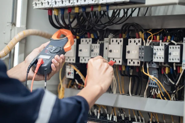 電気工事士は電気キャビネットの制御で電圧と電力線の電流を測定し コンセプトは 電気システムの動作を確認します — ストック写真