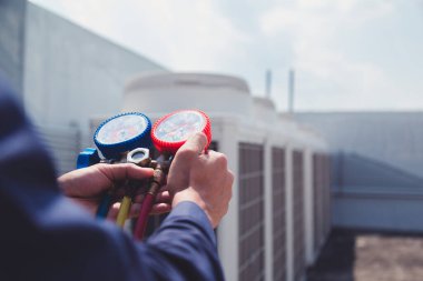 Teknisyen klimayı kontrol ediyor, klimaları doldurmak için ekipmanları ölçüyor..