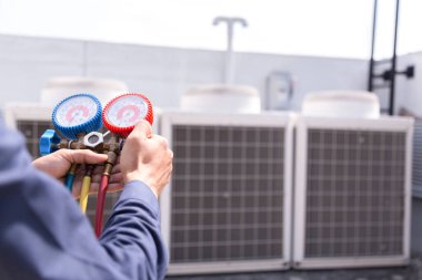 Teknisyen klimayı kontrol ediyor, klimaları doldurmak için ekipmanları ölçüyor..