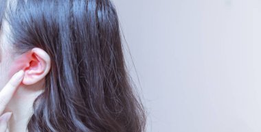 Kadın kulak ağrısı çekiyor. Ağrılı baş kulak ağrısına dokunuyor.