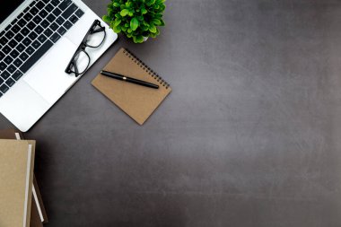 Ofiste çalışma alanı, boş defterli siyah masa ve diğer ofis malzemeleri, kopya alanı olan üst görünüm.