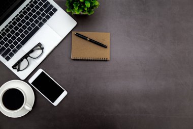Ofiste çalışma alanı, boş defterli siyah masa ve diğer ofis malzemeleri, kopya alanı olan üst görünüm.