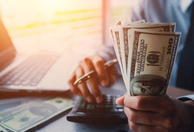 Elinde para, Amerikan doları, yatırımı, başarısı ve karlı iş kavramları olan bir iş adamı.