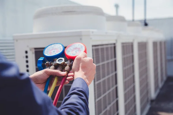 Teknisyen klimayı kontrol ediyor, klimaları doldurmak için ekipmanları ölçüyor..